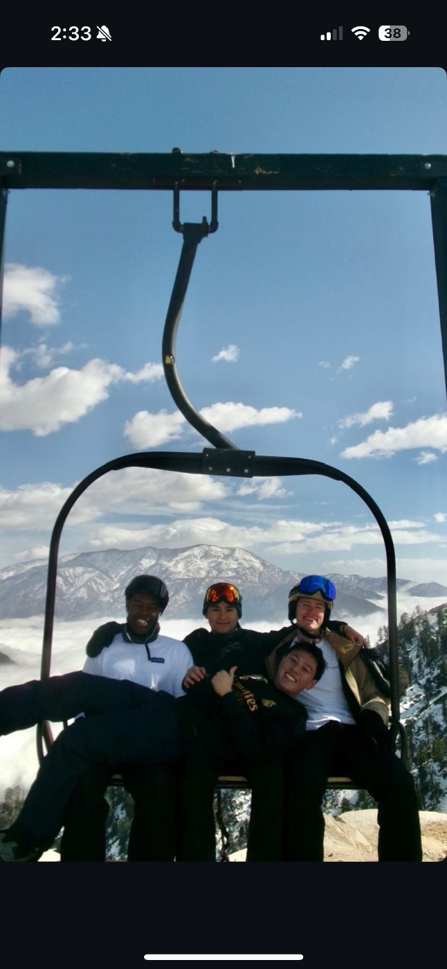 Four friends on a ski lift above the clouds